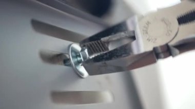 close up view mechanician use pliers tighten a bolt of the car's license plate on the car.install license plate