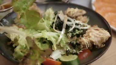 Çatal ve kaşık kullanarak sebze ve kızarmış yengeç kabuğuyla dolu bir kasede salata hazırlıyorum.