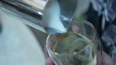 Kahvaltıda kapuçino yapmak için sıcak köpüklü sütü bir fincan taze espresso kahvesine dolduruyorum.