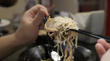 Adam Japon eriştesi yemek için çubuk ve kaşık kullanıyor. Domuz dilimli Japon fast food rameni.