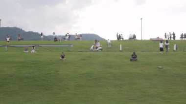 17 Temmuz 2022: Chiang Mai, Tayland: Chiangmai Üniversitesi 'nde günbatımında açık hava aktivitelerinin keyfini çıkaran birçok insanla yeşil çim tarlası ve yamaç tepesi