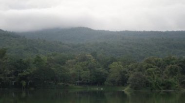 Yeşil dağ sırası ile doğal yeşil rezervuar gölü. Arka planda sis bulutu, Chiang Mai 'de doğal yağmur mevsimi manzarası.