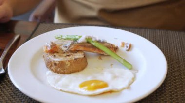 Çatal ve bıçak kullanan bir adam somon bifteği tabağına POV koyarken. Kahvaltı menüsü konsepti