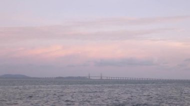Penang Köprüsü 'nün deniz üzerindeki manzarası araba trafiği gün batımında deniz kıyısına yakın parktan otoyola çıkıyor.