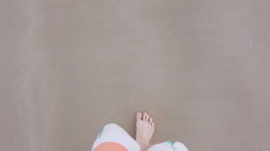 Yaz tatilinde yavaş çekimde beyaz kumsalda çıplak ayakla yürüyen adamın görüntüsü.