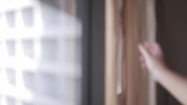 Sabahleyin otel odasındaki büyük pencerenin perdesini kapatırken elin adamının seçici görüntüsü