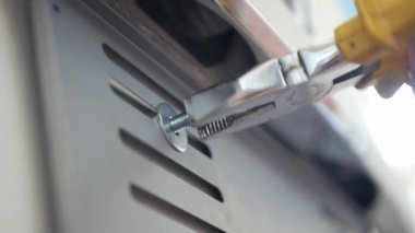 close up view mechanician use pliers tighten a bolt of the car's license plate on the car.install license plate