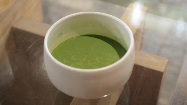 手从桌子上抓起一碗日本风格的新鲜绿茶 在日本咖啡店里喝酒 — 图库视频影像