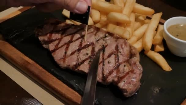 在盘子里用叉子和刀片切牛肉 用薯条 用精美的烤牛排吃饭 — 图库视频影像