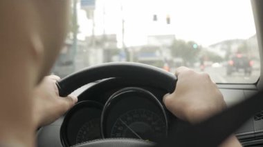 POV with selective focusing to hand holding car's steering wheel while driving a car on local road at Phuket
