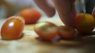 hand use knife cut small baby tomatoes to cook uacamole mexican dipping appetizer. Healthy food