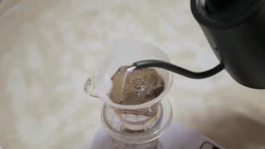 Sabah içeceği olarak ev yapımı demlenmiş kahve yapmak için taze öğütülmüş kahve çekirdeğine kaynar su dökerken video.