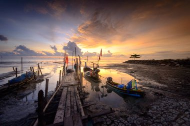 Balıkçı köyünde güneş doğarken balıkçı teknesiyle güzel bir sahil..