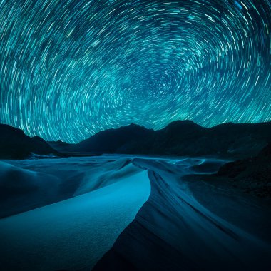 Beautiful blue night desert and dune on star trail background.