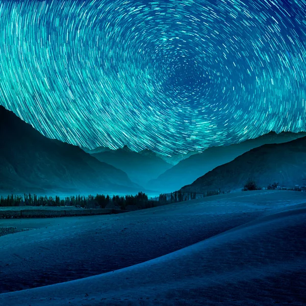 Beautiful blue night desert and dune on star trail background.