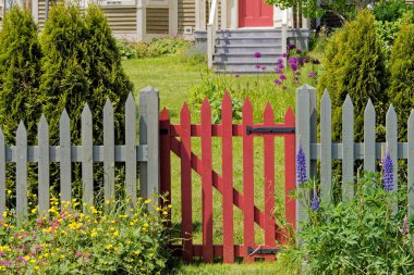 Brightly colored wooden gate with flowers and trees.