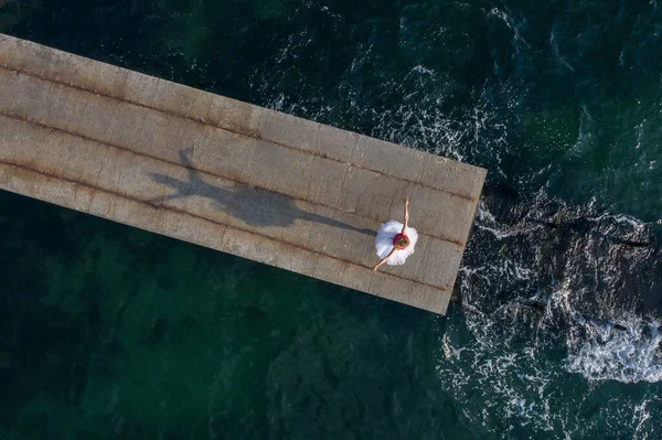 Вид з повітря на танцівницю балету на сонячному морському пірсі — стокове фото