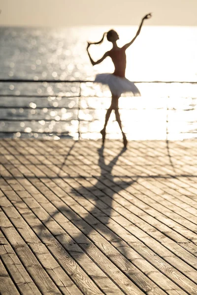 Ombra di ballerina donna sfocata sul molo di legno soleggiato — Foto Stock