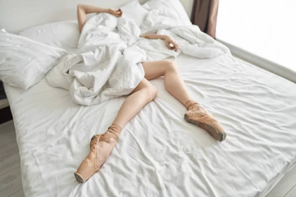 Mulher em sapatos pontiagudos mostra suas pernas e braços de baixo do coverlet — Fotografia de Stock