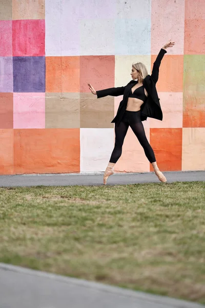 Blondýnka baletní tanečnice pózující vedle barevné stěny — Stock fotografie