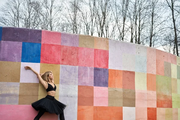 Ξανθός χορευτής μπαλέτου ποζάροντας δίπλα στον πολύχρωμο τοίχο — Φωτογραφία Αρχείου