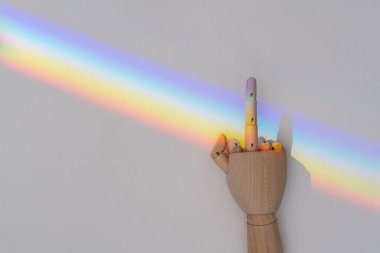 Wooden hand showing fuck you gesture on LGBT community rainbow flag background on a white background. LGBT community support and tolerance concept