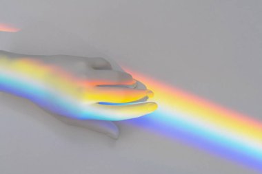 Top view of the white plastic toy hand with rainbow flag like symbol of support sexual lgbt community. LGBT and tolerance concept