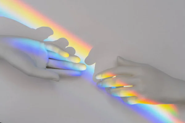 Top view of the rainbow prism reflection inside of the plastic hands. Lgbt flag symbol concept, pride, love and unity. Isolated on white background