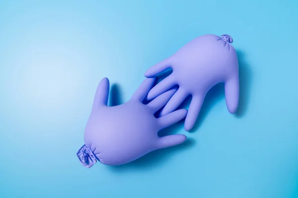 Duas Luvas Látex Insufladas Roxas Seguram Dedos Outro Fundo Azul — Fotografia de Stock