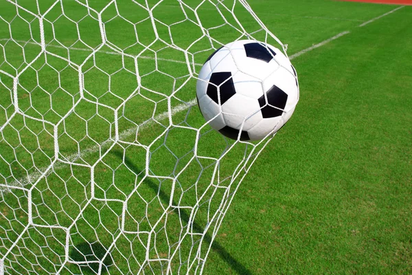 Soccer football in Goal net with green grass field — Stock Photo, Image