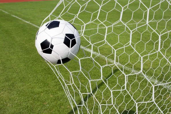 Voetbal voetbal in doel netto met groen grasveld — Stockfoto