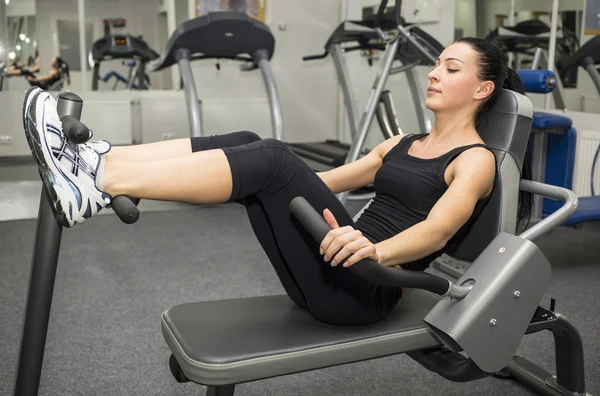 Athletic young woman works out on simulator — Stock Photo, Image