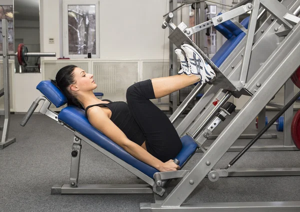 Athletic young woman works out on simulator — Stock Photo, Image