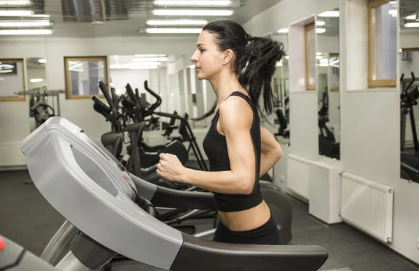 Athletic young woman works out on simulator — Stock Photo, Image