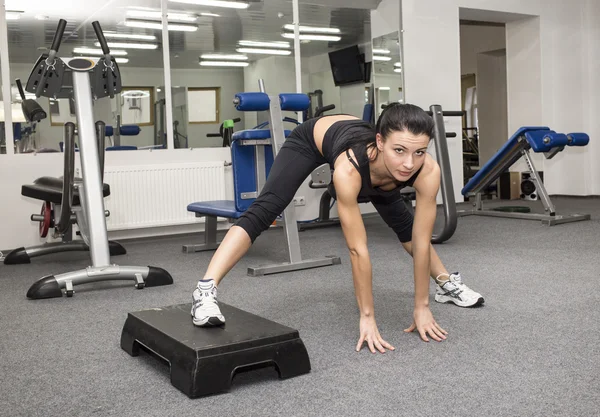 Atlética joven mujer hace ejercicio en simulador — Foto de Stock