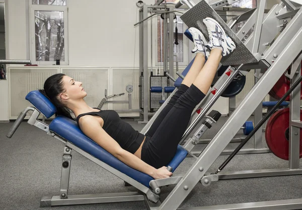 Athletic young woman works out on simulator — Stock Photo, Image