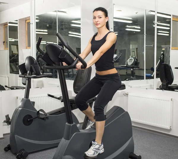 Atletische jonge vrouw werkt op simulator — Stockfoto