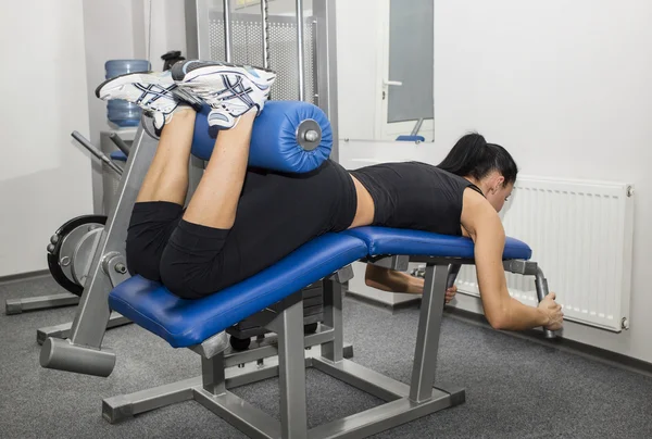 Athletic young woman works out on simulator — Stock Photo, Image