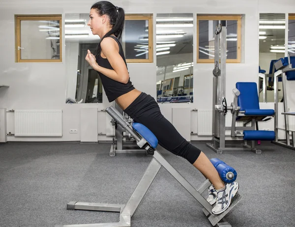 Athletic young woman works out on simulator — Stock Photo, Image