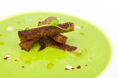 restoranda beyaz bir tabak üzerinde croutons bezelye çorbası