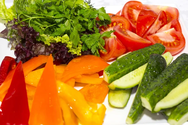 Cucumbers and tomatoes on a white plate on a table in a restaurant — Stock Photo, Image