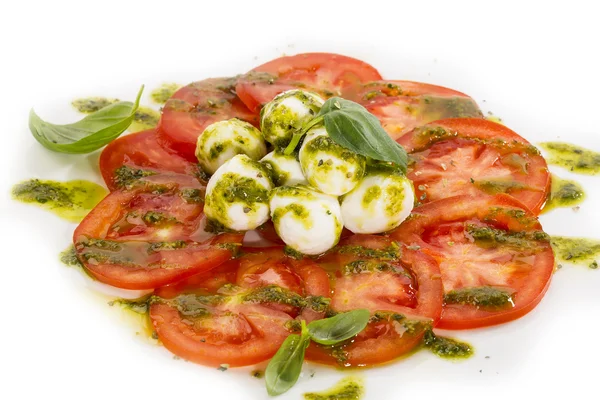 Tomaatteja juustokastikkeella kaadetaan valkoiselle lautaselle ravintolassa — kuvapankkivalokuva
