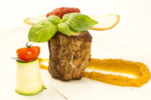 Baked meat with sauce and garnish on a plate in a restaurant — Stock Photo, Image