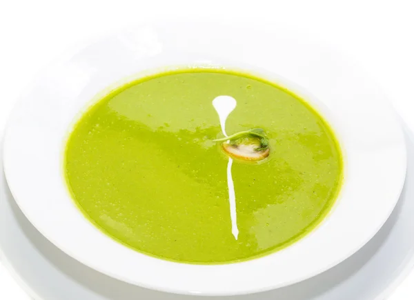 Sopa de ervilha decorada com cogumelos e verde em uma placa branca em um restaurante — Fotografia de Stock