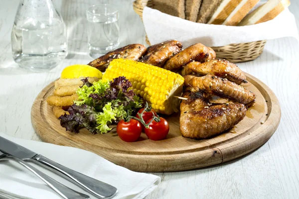 Les ailes de poulet sont grillées sur un plateau en bois — Photo