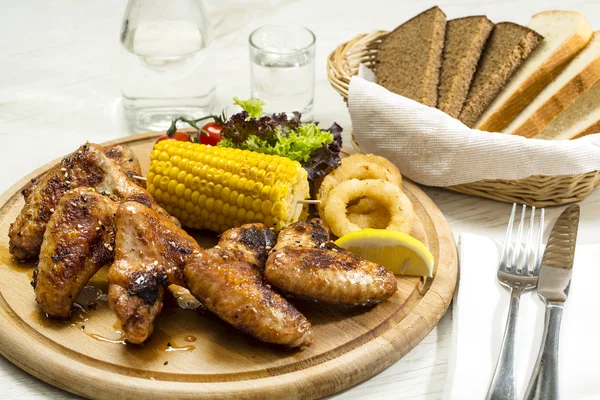 Ali di pollo sono alla griglia su un piatto di legno — Foto Stock