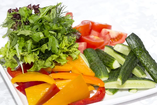 Cucumbers and tomatoes on a white plate on a table in a restaurant — Stock Photo, Image