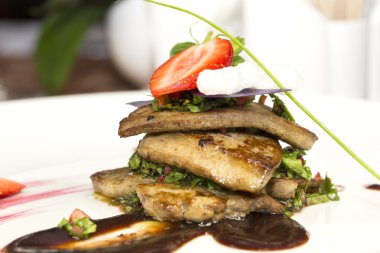 kızartma kaz ciğeri, yeşillik ve çilek ile süslüdür.