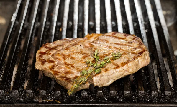 Cooking beef steak on a grill in the restaurant — Stock Photo, Image