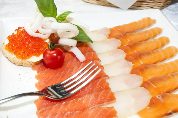 Sanduíches com caviar e peixe fatiado em um prato branco — Fotografia de Stock